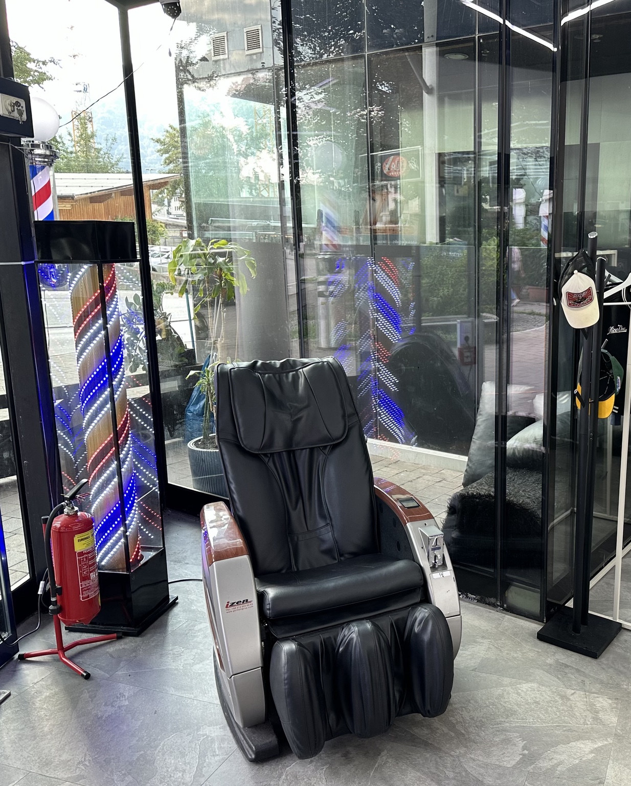 Massagesessel im Wartebereich von MAX Herrenfriseur neben beleuchteter Barber-Pole