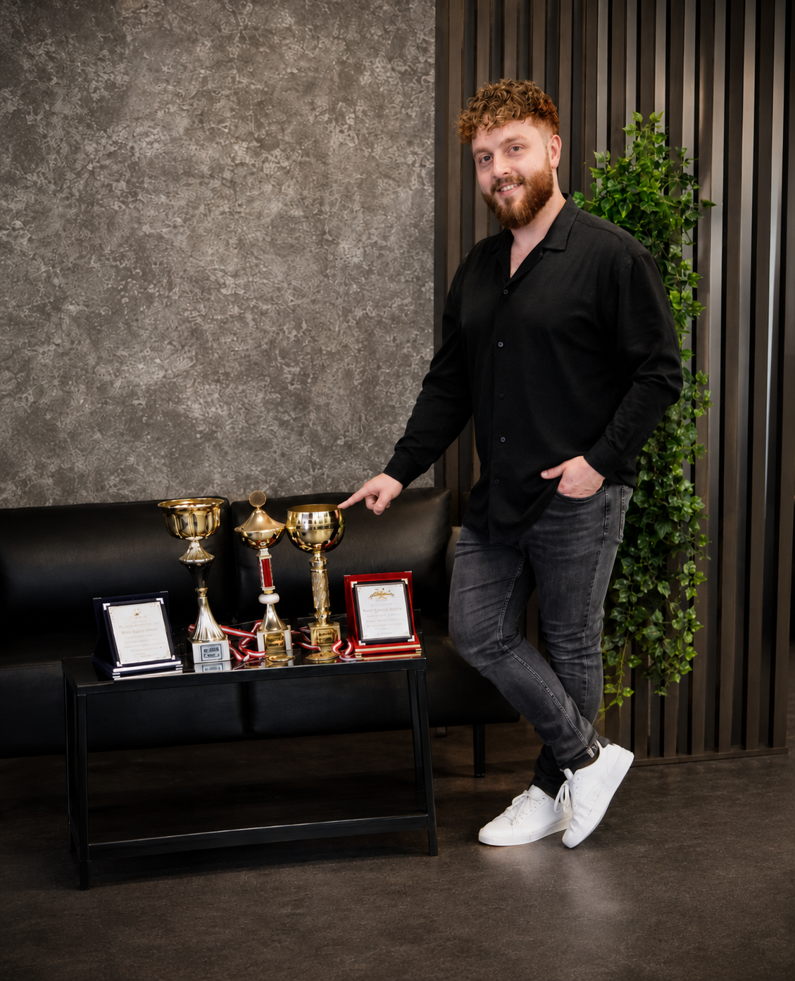 Tunahan, Inhaber von MAX Herrenfriseur Wörgl, mit seinen Pokalen und Auszeichnungen